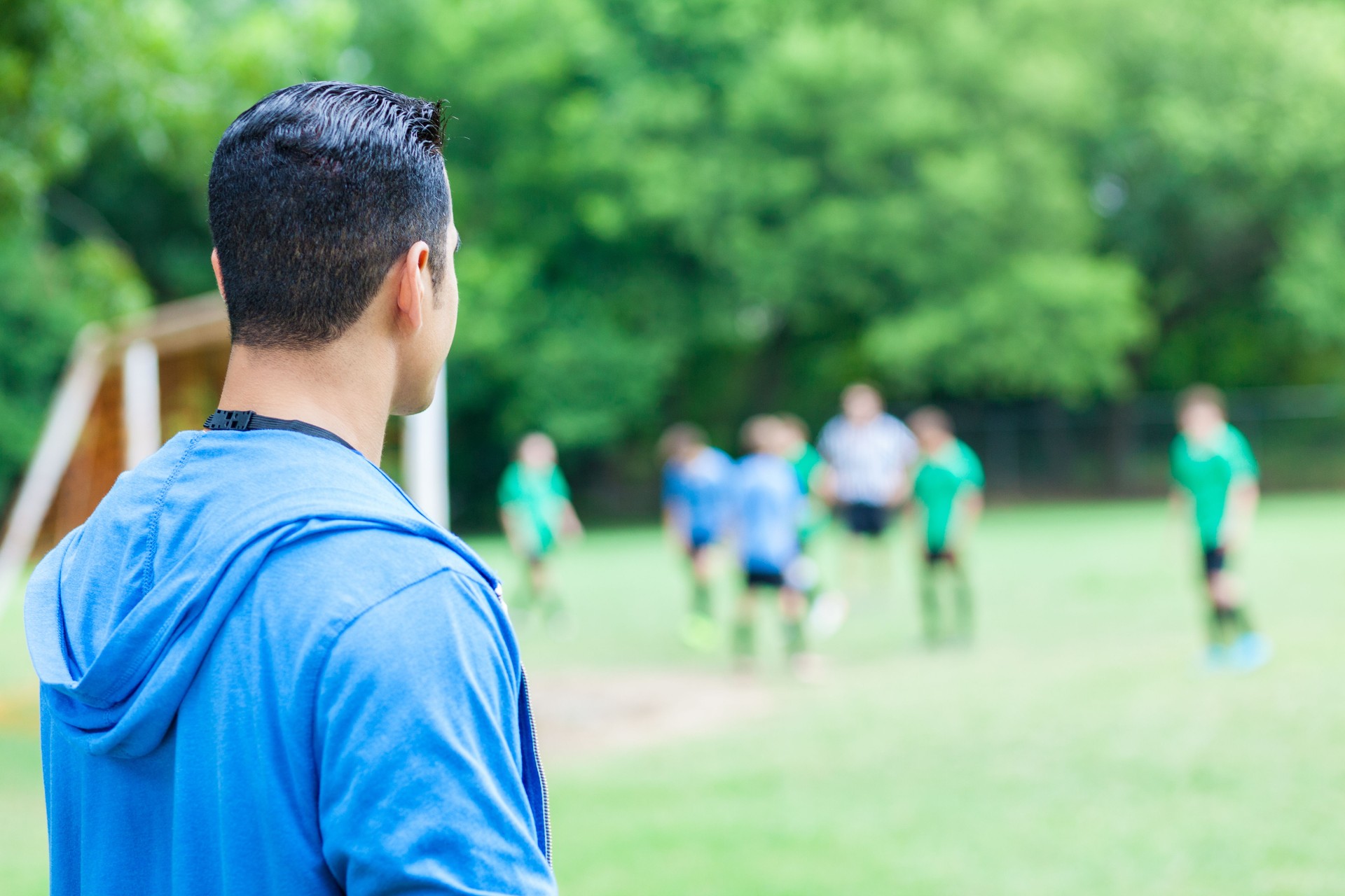 L’entraîneur se tient sur la touche en regardant son équipe de soccer jouer